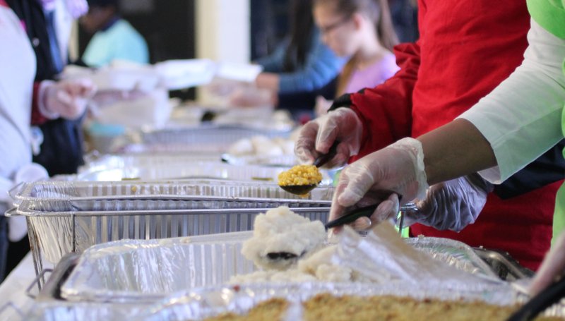 Volunteers serve out food into styrofoam boxes to be sent out to families in need this holiday. 
