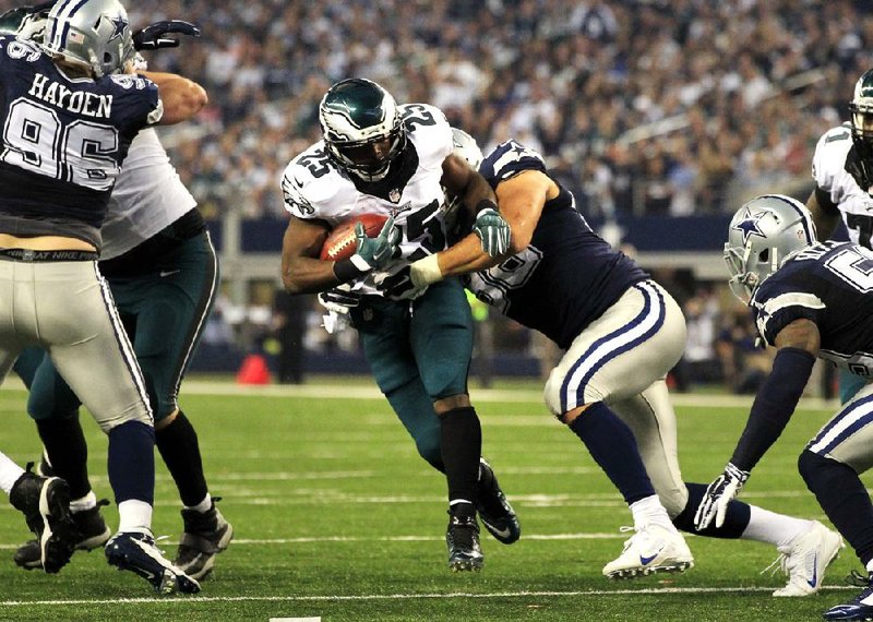 Philadelphia Eagles running back LeSean McCoy (25) is tackled by Dallas Cowboys defensive tackle Tyrone Crawford (98) after a short run during the first half of an NFL football game, Thursday, Nov. 27, 2014, in Arlington, Texas. (AP Photo/John F. Rhodes)