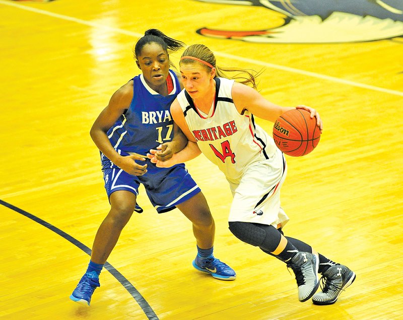  Staff Photo Michael Woods Emilie Jobst, right, Rogers Heritage guard, drives past Bryant defender Lauren Carroll during the first half Nov. 24 at Heritage in Rogers.