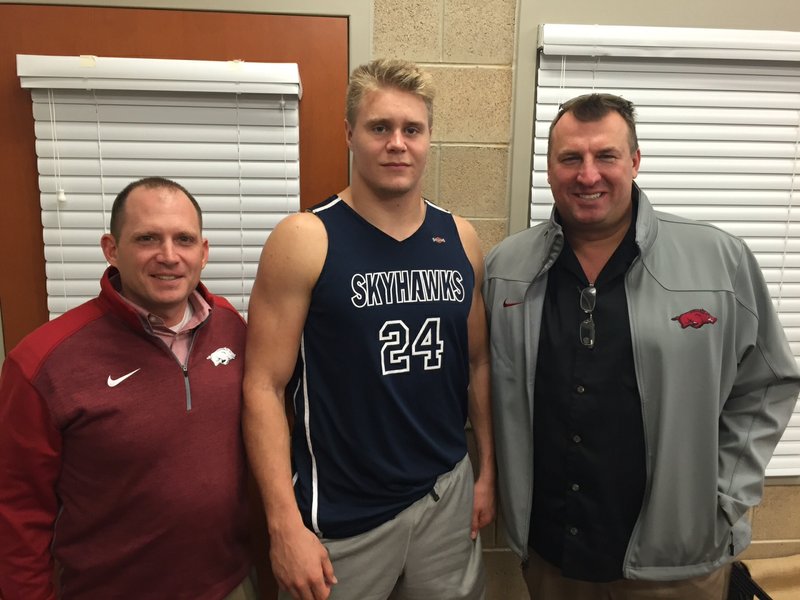Arkansas defensive coordinator Robb Smith, linebacker-defensive end Porter Gustin and Coach Bret Bielema pose for a picture in a coach's office. 