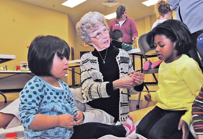 STAFF PHOTO FLIP PUTTHOFF Dott Webb plays Thursday with Viviana Sarmiento, left, and Hayden Brunson, right, at the Sunshine School and Development Center in Little Flock. Webb has worked at the school, founded by her family, for 50 years