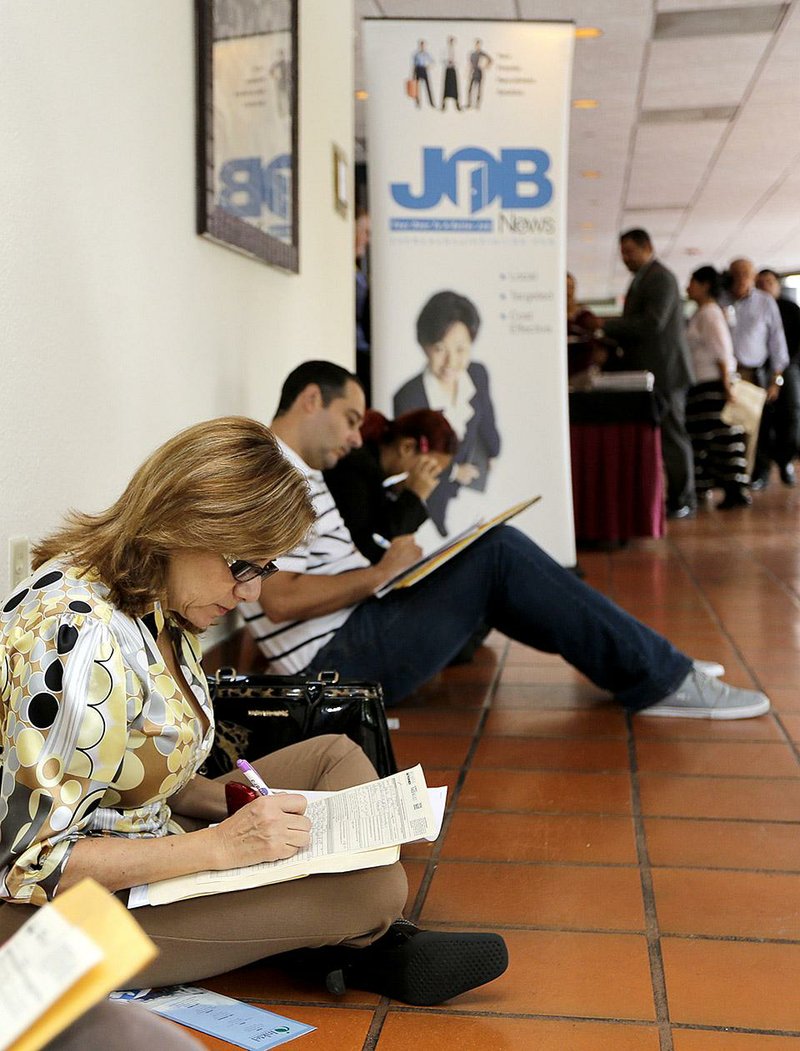 Job seekers work on applications at a career fair in Miami Lakes, Fla., in October. Some 44,000 more jobs were added in September and October combined in the United States than previously estimated, the Labor Department said Friday. 