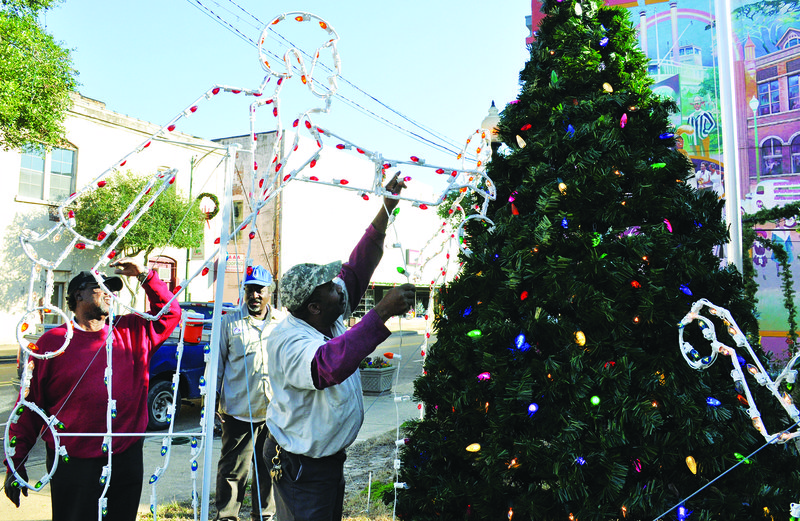 City of Camden employee John Pace, right, strings Christmas lights on the display in the city park downtown as Park Supervisor Nathion Jenkins, left, and Matt Thompson, center, look on.
