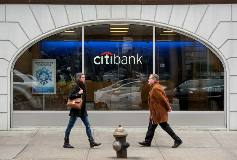 Pedestrians pass a Citibank branch Monday in New York. The bank said Tuesday that it expects to turn a fourth-quarter profi t despite $3.5 billion in charges for legal and restructuring costs. 