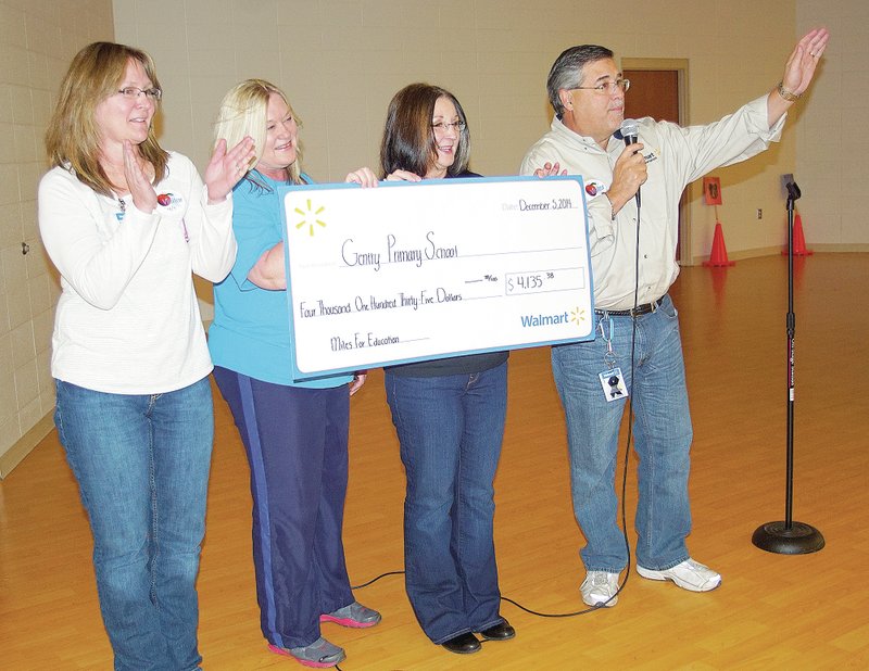 Photo by Randy Moll Debbie Hall, a human resources manager at the Walmart dispatch office (left) and Bob Dixon, general transportation manager for Walmart&#8217;s private fleet (right), present a check to Gentry Primary School in the amount of $4,135.38. The money was raised by safe driving on the part of Walmart truck drivers. The check was received by Dea Ann Heinen, school counselor, and Gayla Wilmoth, school principal, during a scheduled assembly on Friday.