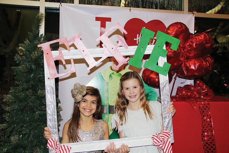 Marisol Sela of Maumelle, left, and Anna Beth Jeane of Wooster pose for an “elfie” with a poster of Buddy, the lead character in Elf, the musical, at The Rep in Little Rock. The girls both play elves and appear in other scenes as “normal” girls, Marisol said. Marisol is the daughter of Missy and Alvaro Sela, and Anna Beth is the daughter of Tracy and Chad Jeane.