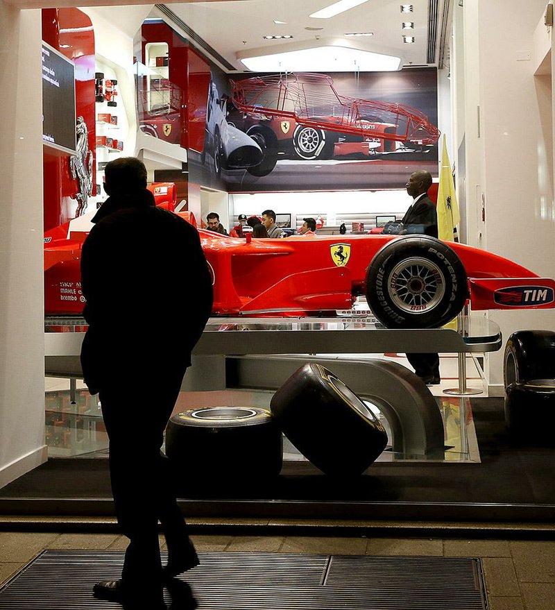 A man watches outside a shop window of a Ferrari Store in Milan, Italy, Tuesday, Dec.9, 2014. Ferrari’s sleek sports cars and souped-up Formula 1 racing machines have made the prancing horse logo among the world’s most powerful brands. Now, as the company prepares for a public listing, it wants to cash in on the cachet. The aim: position Ferrari not just among its car-making peers, but as a luxury goods company. Think Armani, Hermes ... Ferrari. Analysts say that could mean refining its line of merchandise, expanding upon a theme park franchise or creating a chain of members’ clubs and hotels catering to the rich. Chairman Sergio Marchionne will present his vision to investors in the coming weeks, but the potential already has two worlds spinning in anticipation. (AP PhotoAP Photo/Luca Bruno)