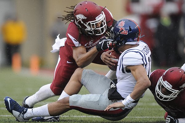 Arkansas' Alan Turner, left, and Tevin Mitchel, right, stop Ole Miss' Evan Engram in the first quarter of a game Saturday, Nov. 22, 2014 at Razorback Stadium in Fayetteville. 