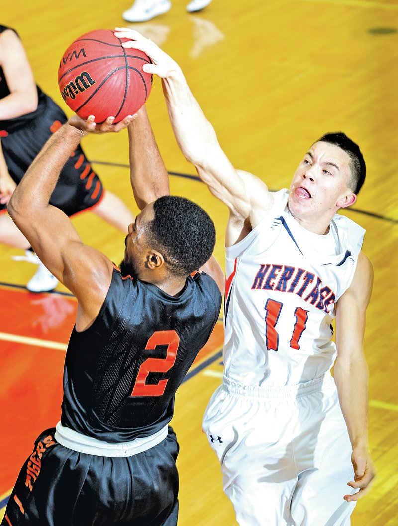  STAFF PHOTO JASON IVESTER Chris Coover, Rogers Heritage senior, blocks a shot attempt by Waynesville (Mo.) senior Rashad Swanson on Friday during the Arvest Hoopfest tournament at Rogers Heritage. Coover was charged with a foul on the play. See more photos at nwaonline.com/photos.