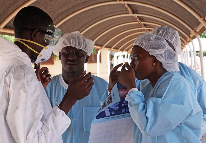 In this file photo taken Saturday, Oct. 25, 2014, a  health worker, right, briefs another, left, on the use of their Ebola security gear before working with diseased Fanta Kone at a Ebola virus center in  Kayes, Mali. The last Ebola patient being treated in Mali has survived the disease and been released, the Health Ministry said Friday, Dec. 12, 2014. 