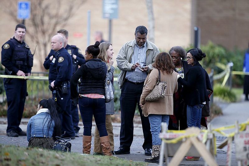 Officials speak to people at the scene of a shooting Friday at Rosemary Anderson High School in Portland, Ore. 