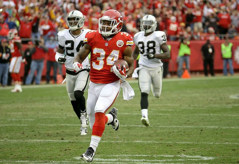 Kansas City Chiefs running back Knile Davis (34) runs for a touchdown ahead of Oakland Raiders free safety Charles Woodson (24) and cornerback T.J. Carrie (38) during the second half of an NFL football game in Kansas City, Mo., Sunday, Dec. 14, 2014. (AP Photo/Charlie Riedel)