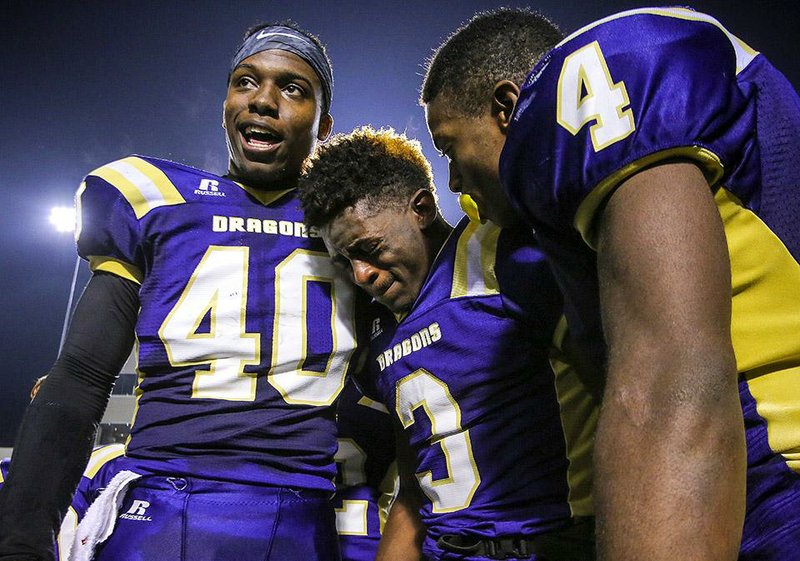 Junction City running back JaQwis Dancy (3) shares an emotional moment with teammates Josh Armstrong (4) and Jamario Bell after the Dragons’ 38-6 victory over Hazen in the Class 2A championship game Saturday night at War Memorial Stadium in Little Rock. 