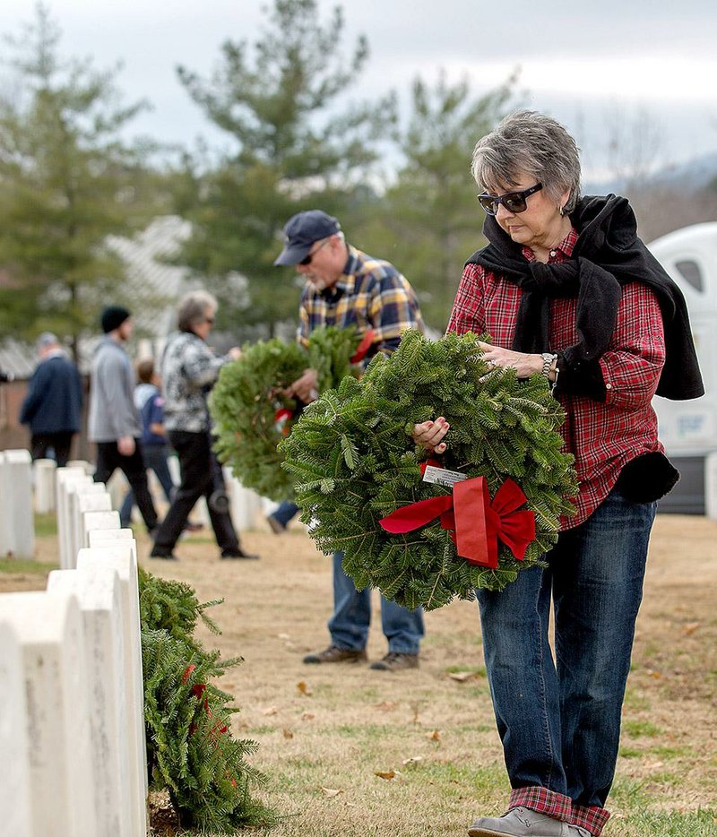 Latrice Sherman and her husband, Fred, both of Fayetteville, place wreaths at headstones Saturday after the Wreaths Across America ceremony at the veterans cemetery in Fayetteville. 