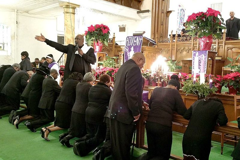 Pastor Henry A. Belin III, standing left, pastor at First AME Church: Bethel, prays over members of his congregation, Sunday, Dec. 14, 2014 in New York. Congregants in African-American churches across the country wore black to Sunday services and prayed over the men in attendance in a symbolic stand against fatal police shootings of unarmed black men. (AP Photo/Verena Dobnik)