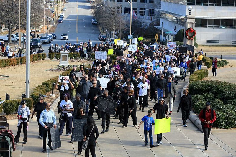 About 100 people marched Saturday along Capitol Avenue in Little Rock to the steps of the state Capitol in a peaceful protest of the deaths of unarmed black men at the hands of police in Missouri and New York. 