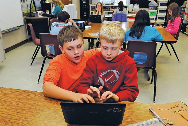 STAFF PHOTO FLIP PUTTHOFF Konrad Stouffer, left, and Seth Wagahoff work on a computer project together Thursday while studying in Christie Price&#8217;s fourth-grade classroomxat Reagan Elementary School in Rogers.