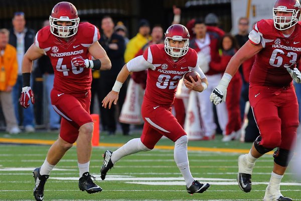 Arkansas punter Sam Irwin-Hill, center, rolls out for yardage Friday, Nov. 28, 2014, after faking a punt in the third quarter against Missouri in Columbia, Mo.