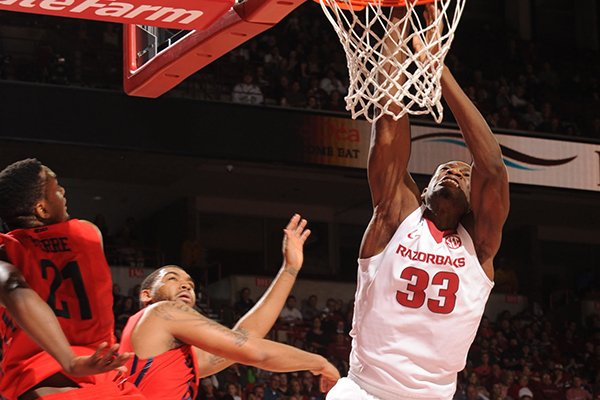 Arkansas' Moses Kingsley (33) attempts to dunk the ball as he is hit by Dayton's Dyshawn Pierre, left, during the second half Saturday, Dec. 13, 2014, at Bud Walton Arena in Fayetteville.