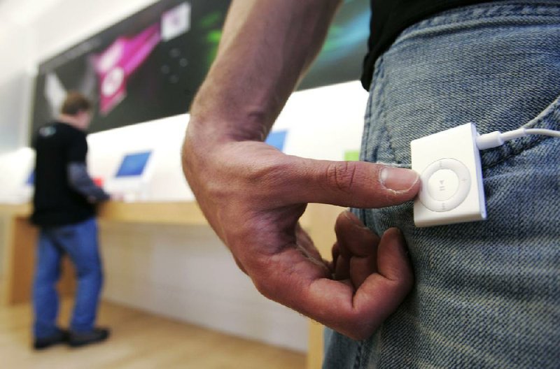 A man uses an Apple iPod Shuffle at an Apple store in Palo Alto, Calif., in this 2006 fi le photo. A jury Tuesday in California found in favor of Apple in a class-action lawsuit over iTunes software that blocked songs from competing music stores. 