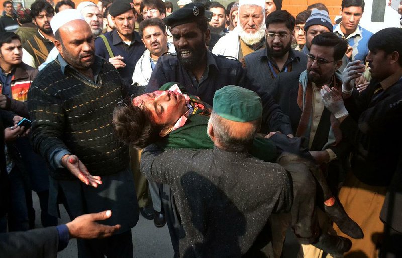 Guards at a hospital in Peshawar, Pakistan, carry a student who was injured in an attack on his school by Taliban gunmen. “My son was in uniform in the morning. He is in a casket now,” one parent wailed. 