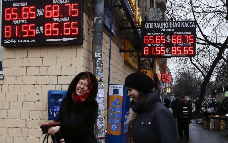 Signs advertising currency exchange rates hang from an office in Moscow on Tuesday. Russia’s central bank on Tuesday raised the nation’s prime interest rate to 17 percent from 10.5 percent.