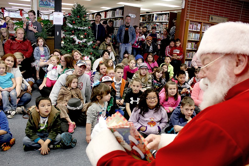 Tina Parker/Herald-Leader Santa read &#8216;T&#8217;was the Night Before Christmas&#8217; to a group of nearly 100 children and parents who crammed into the Siloam Springs Library. It is Santa&#8217;s 12th year to visit the library.