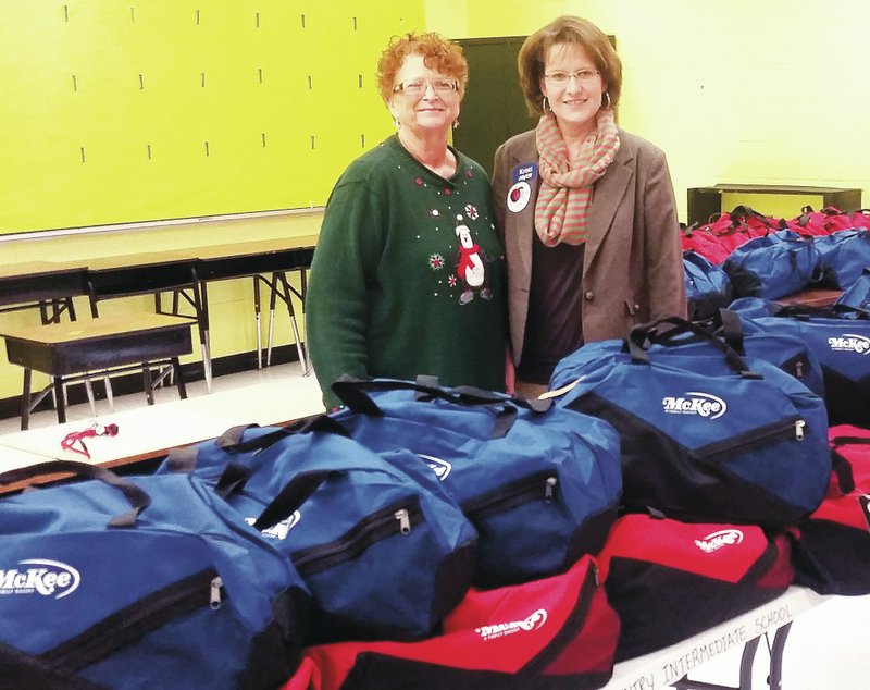 Submitted Photo Jo Derwin, intermediate school counselor (left), and Kristi Hollaway, Arvest Bank branch manager in Gentry, stand with some of the 102 packs the bank provides every year with the help of partner McKee Foods, which donates funds and the backpacks used in the program. Arvest Bank in Gentry supplied snack packs to the Gentry elementary and intermediate schools for the holiday break. The packs, filled with easy-to-prepare foods such as easy macaroni and cheese, apple sauce, crackers, ravioli, oatmeal, granola bars and other nutritious items, are intended for children at risk for some food insecurity over the long holiday break away from school-provided breakfasts and lunches.