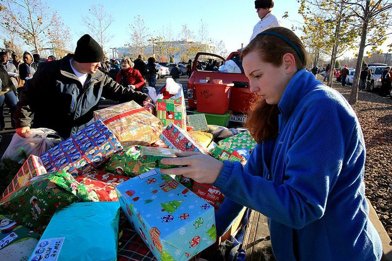 Volunteers and a stream of cars and trucks will descend on the Clinton Presidential Center to provide gifts, necessities and meals for the homeless and near-homeless at the annual Christmas Caravan, 8 a.m.-noon Saturday. Here, volunteers Alex Hale (left) and Jessica Gates sort through gifts at last year’s event. 
