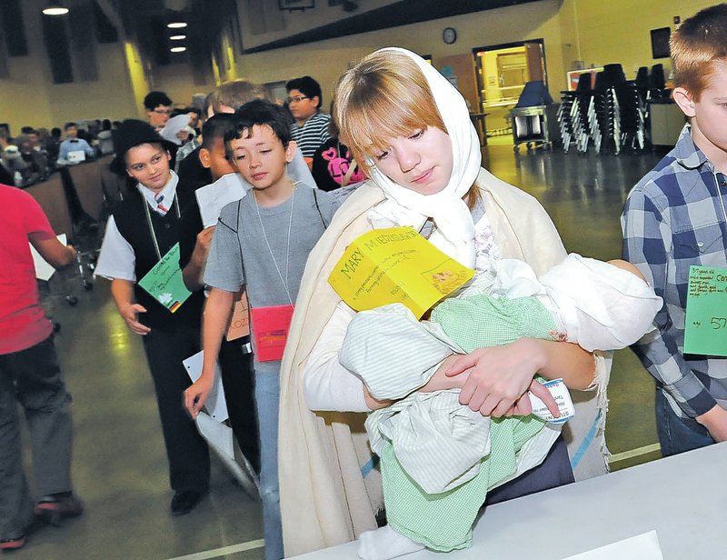 STAFF PHOTO FLIP PUTTHOFF Abigail Miller plays the role of an immigrant from Poland during the Ellis Island re-enactment Wednesday at Ruth Barker Middle School in Bentonville.