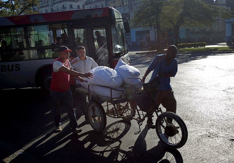 Men push a tricycle with a platform in the back for transporting goods in Havana on Thursday. Cuba’s poor economy will make investment difficult for some businesses should the U.S. embargo of the island nation be lifted.