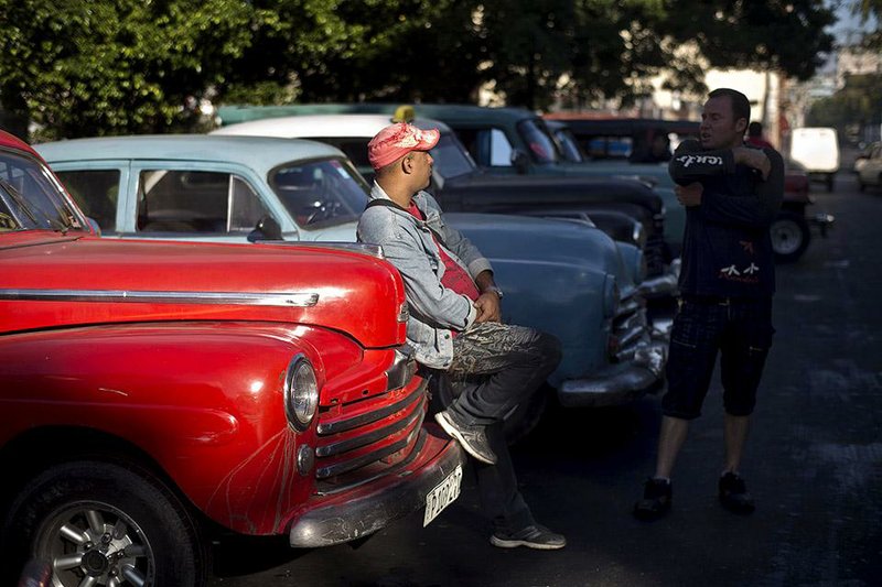 Cuban taxi drivers wait for clients near their antique American cars Thursday in Havana. 