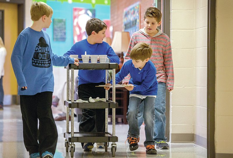 STAFF PHOTO JASON IVESTER Graham Hardin, from left, Logan Mullins, Theodore Haven and Strael Wolfe take a cart with hot chocolate to be delivered to classrooms.