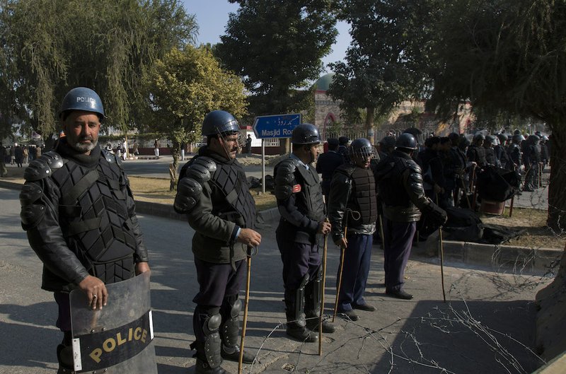 Pakistani police officers stand guard outside radical Red Mosque as supporters of Pakistani religious party Ahle Sunnat Wal-Jammat express solidarity with families of the students killed in Tuesday's attack on a military-run school in Peshawar, during a rally in Islamabad, Pakistan, on Friday, Dec. 19, 2014. 