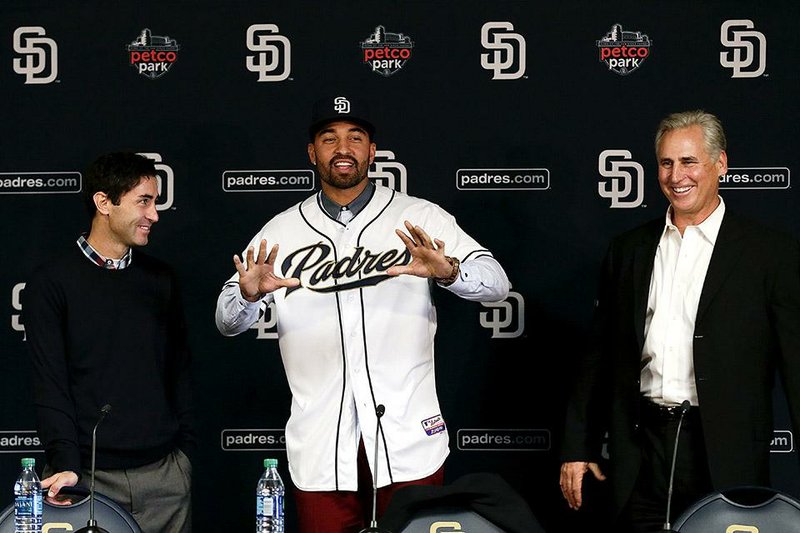 San Diego Padres outfielder Matt Kemp (center) tries on his new jersey with manager Bud Black, right, during a news conference Friday in San Diego. Kemp’s addition to the the team is just one of a handful of moves made by Padres General Manager A.J. Preller (left), who also has added outfielder Wil Myers, the 2013 AL Rookie of the Year, from Tampa Bay and All-Star catcher Derek Norris from Oakland.