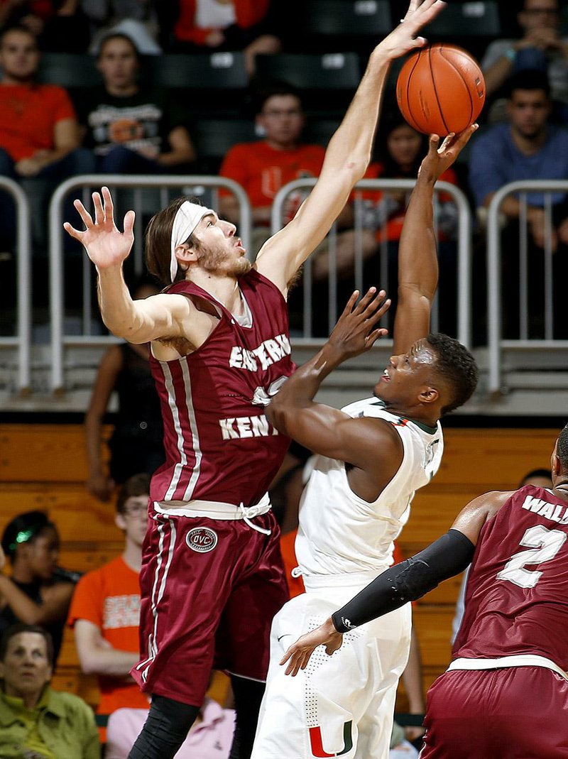 Eastern Kentucky’s Eric Stutz (left) blocks a shot by Miami’a Deandre Burnett during Friday night’s game. The unranked Colonels defeated the No. 18 Hurricanes 72-44. 