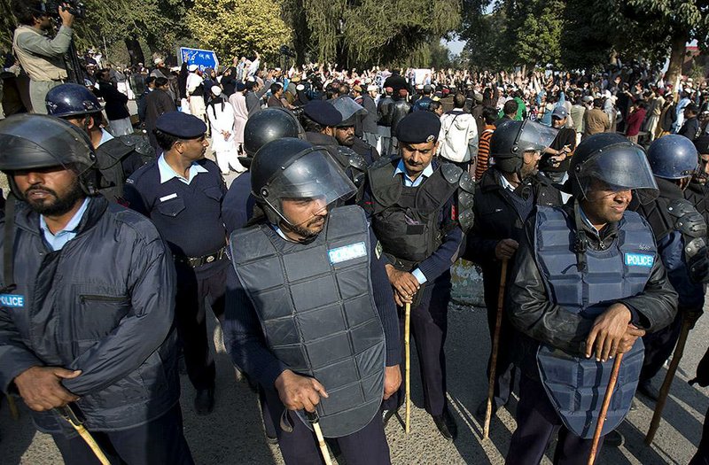 Police officers stand guard in Islamabad during a rally Friday in support of the families of students killed in Tuesday’s attack on a military-run school in Peshawar. 