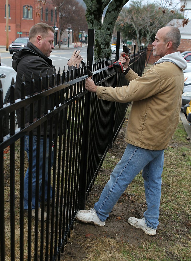 The Sentinel-Record/Richard Rasmussen GETTING REDDIE: Summit Properties construction crew employees Harold James, left, and Joe Wells place a section of fence into place at the Landmark Building on Thursday. Renovation plans, which included the use of fencing to define the campus, for the new Downtown HSU/NPCC Education Center were revealed earlier this year. Classes are planned to be held in the Landmark Building beginning in the spring semester.