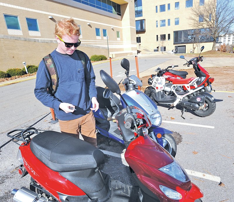 STAFF PHOTO ANDY SHUPE Lachlan Moore, a junior from Australia at the University of Arkansas&#8217; Walton College of Business, prepares to leave on his scooter Monday on the campus in Fayetteville. The City Council will consider Tuesday an ordinance requiring scooter drivers to have liability insurance for their vehicles.