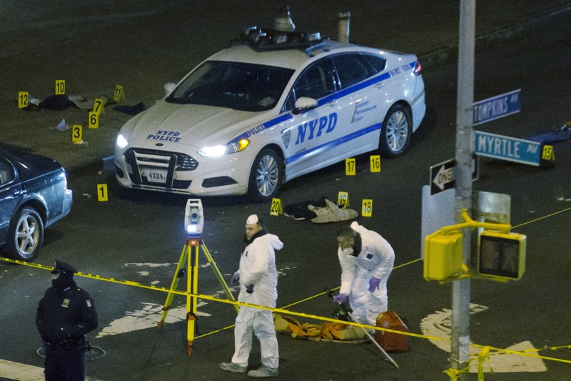 Investigators work at the scene where two NYPD officers were shot, Saturday, Dec. 20, 2014 in the Bedford-Stuyvesant neighborhood of the Brooklyn borough of New York. Police said an armed man walked up to two officers sitting inside the patrol car and opened fire before running into a nearby subway station and committing suicide. Both police officers were killed. 