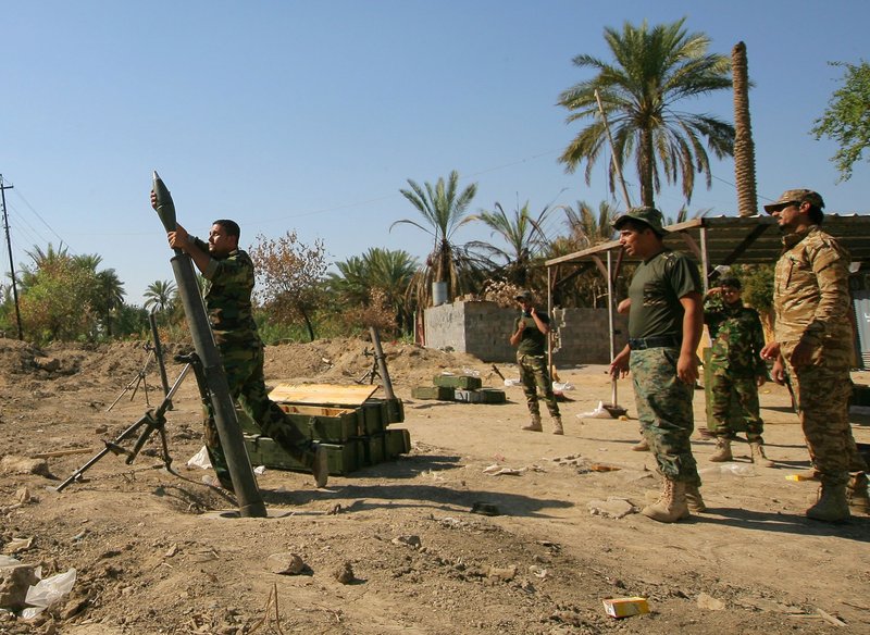 In this Wednesday, Sept. 24, 2014 file photo, fighters from a militant Shiite group known as Asaib Ahl al-Haq, or League of the Righteous, fire a mortar round towards positions of militants from the Islamic State group on the front line in Jurf al-Sakhar, 43 miles (70 kilometers) south of Baghdad, Iraq. The Shiite fighters are credited for curbing the Sunni militants advance on Baghdad and the surrounding areas and for achieving significant progress on the ground, including breaking the extremists' siege on the northern Shiite-majority town of Amerli in August and later, in operations to liberate Jurf al-Sakher, a town south of Baghdad. 