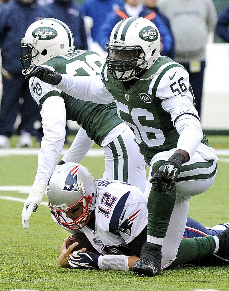 New England Patriots quarterback Tom Brady (12) reacts after being sacked by New York Jets' Antonio Allen (39) and Demario Davis (56) during the first half of an NFL football game Sunday, Dec. 21, 2014, in East Rutherford, N.J. (AP Photo/Bill Kostroun)