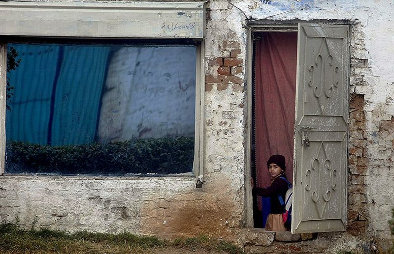 A Pakistani student peers through a door Saturday as he returns home from school in Peshawar.