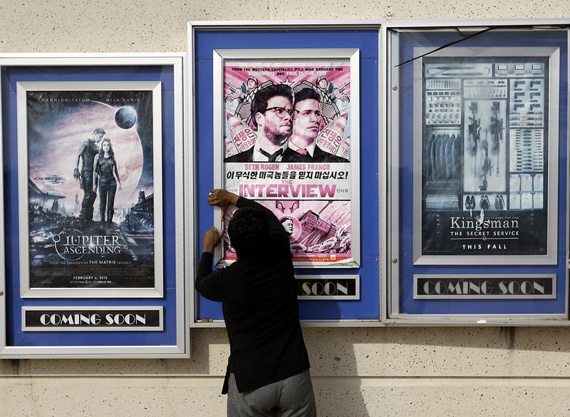FILE - In this Wednesday, Dec. 17, 2014 file photo, a worker removes poster for the movie "The Interview" from a display case at a Carmike Cinemas movie theater in Atlanta. The Alamo Drafthouse in Texas and Atlanta's Plaza Theater on Tuesday, Dec. 23, 2014 said they will begin showing "The Interview" on Christmas Day, seemingly putting the comedy back in theaters after Sony Pictures Entertainment canceled its release. The Plaza is independently owned and not part of the Carmike chain.
