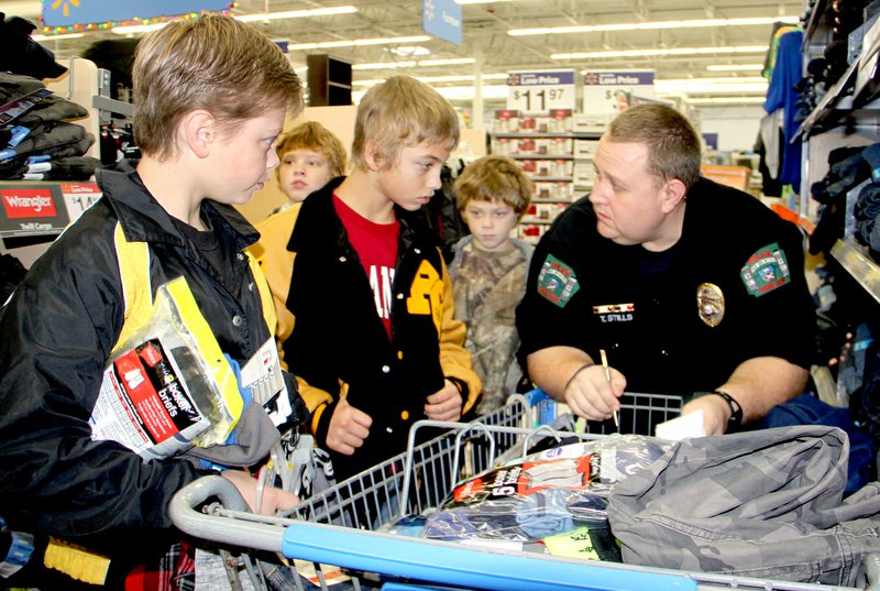 LYNN KUTTER ENTERPRISE-LEADER Prairie Grove police officer Travis Stills helps four brothers shop for new school clothes: Brian, left, Robbie, Corey and Lance Phipps. The boys said they liked being able to pick out their own items. Prairie Grove helped 50 children this year through its Shop with a Cop program.