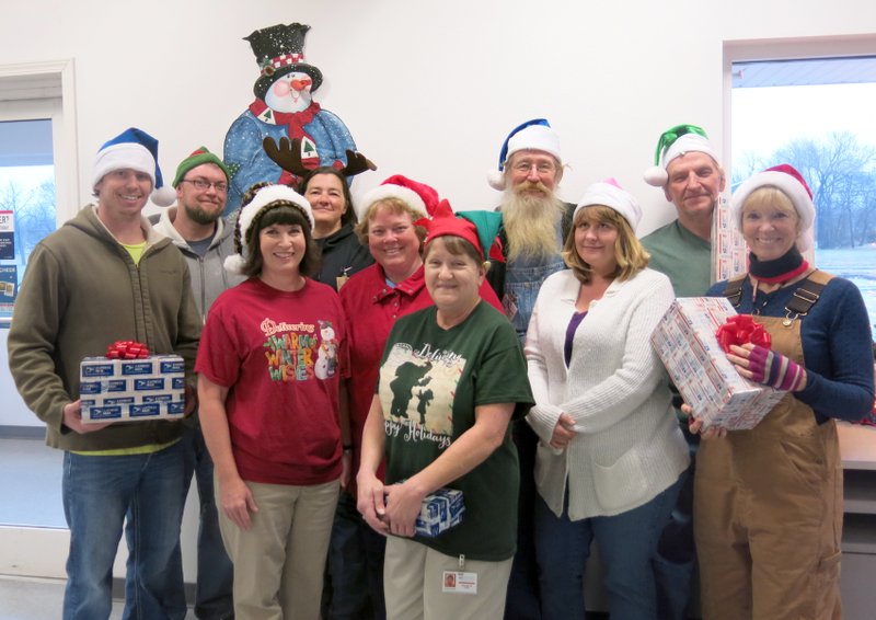 Photo by Susan Holland While everyone else is enjoying the season, employees of the post office department are having their most hectic time of the year. Clerks at the Gravette post office say they are processing more packages this year than ever before. Despite the heavy work load, the Gravette crew put on its holiday headgear and posed for a photo Thursday morning before carriers went out on their routes. Pictured are acting postmaster Kyle Austin (far left), clerks Lorrie Amos and Karen Wilkins (left front), truck driver Carol Jameson (right), and mail carriers Paul Martin, Anita Young, Michelle Howard, Roy Ford, Tammy Campbell and Danny Boling.