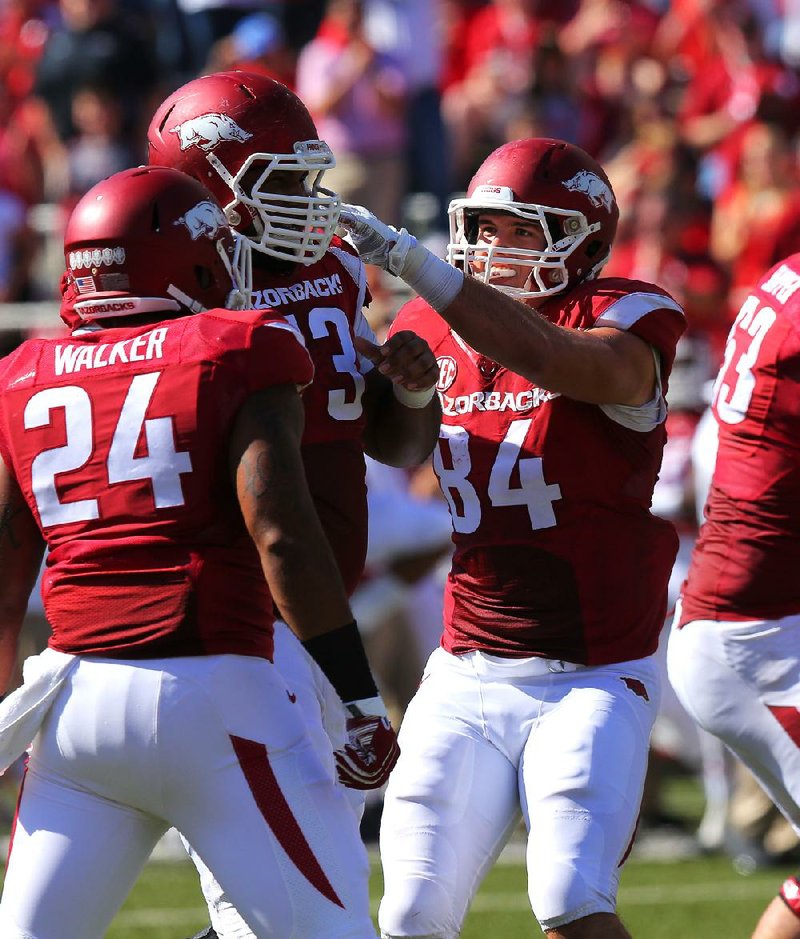 Arkansas offensive lineman Sebastian Tretola (73, center) is congratulated by teammates after throwing a touchdown pass to long snapper Alan D’Appollonio against Alabama-Birmingham on Oct. 25. Tretola, 6-5, 340 pounds, did the Heisman Trophy pose after the touchdown pass. 