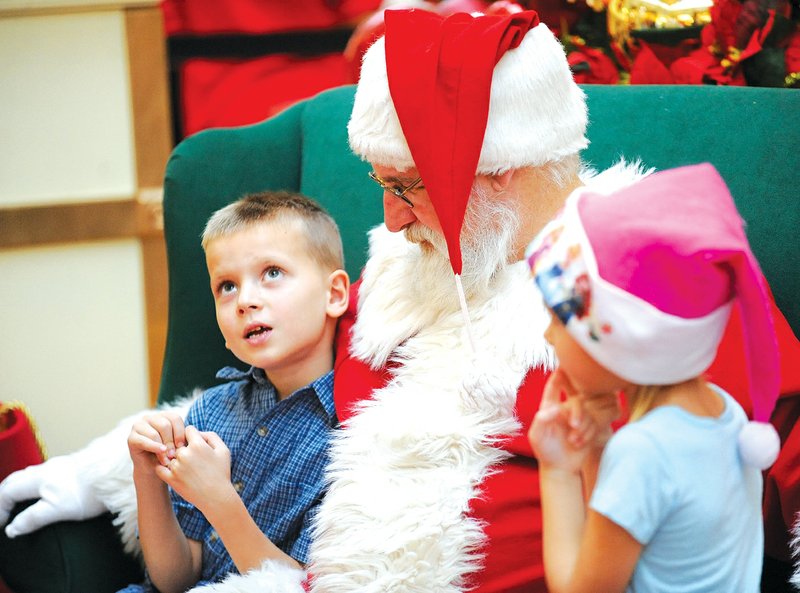Joshua Phillips, 7, of Springdale, left, pauses to think of what he wants for Christmas as Santa Claus and Joshua’s 5-year-old sister, Cyan, listen Monday in the Northwest Arkansas Mall in Fayetteville.