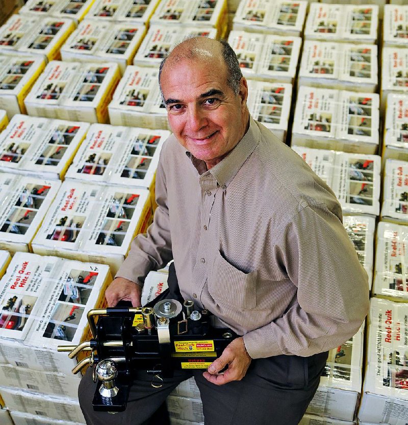 Arkansas Democrat-Gazette/JOHN SYKES JR. - Mike Rebick, who developed over the past ten years his patented "Reel-Quik Hitch," holding the device while sitting atop boxed hitches in his west Little Rock workshop.
