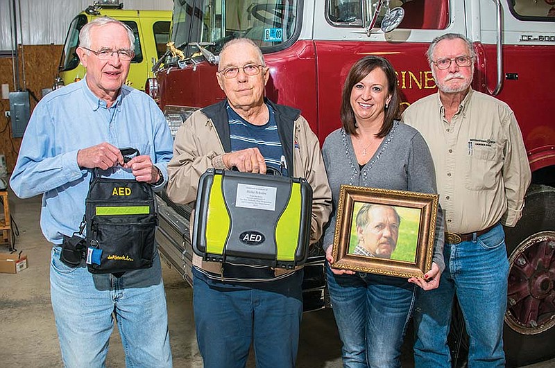 Tesa Schales Naylor holds a photo of her late father, Ricky Schales. In memory of her father and with the help of family and friends, Naylor raised enough money to purchase two automated external defibrillators for the New DeRoche Volunteer Fire Department. Representing the Fire Department are, from left, Fire Chief Paul Sullivan; John Nannemann, president of the Fire Department’s board of directors; and Leslie Burris, secretary-treasurer of the board of directors.